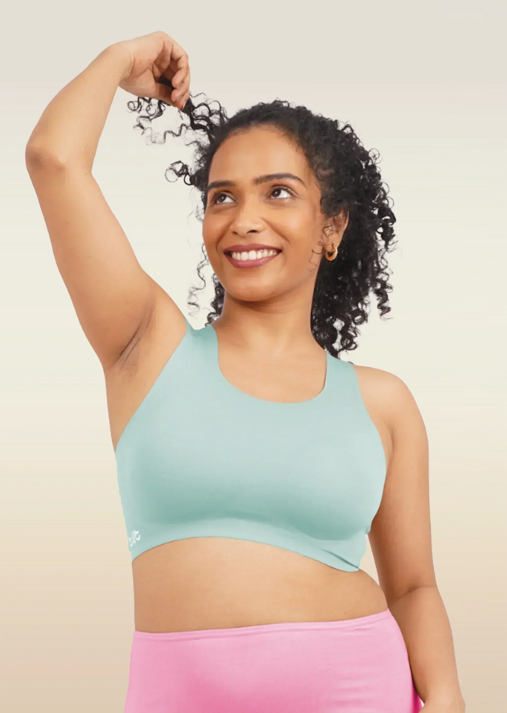 Woman wearing a blue sports bra and pink underwear on a beige background