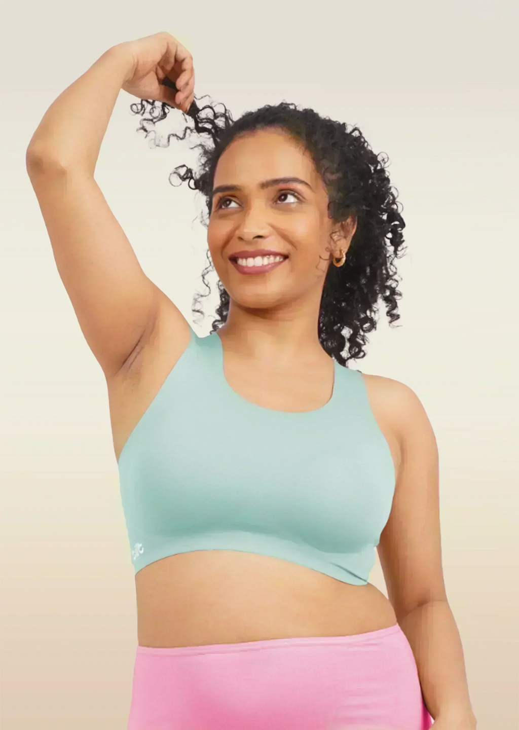Woman wearing a blue sports bra and pink underwear on a beige background