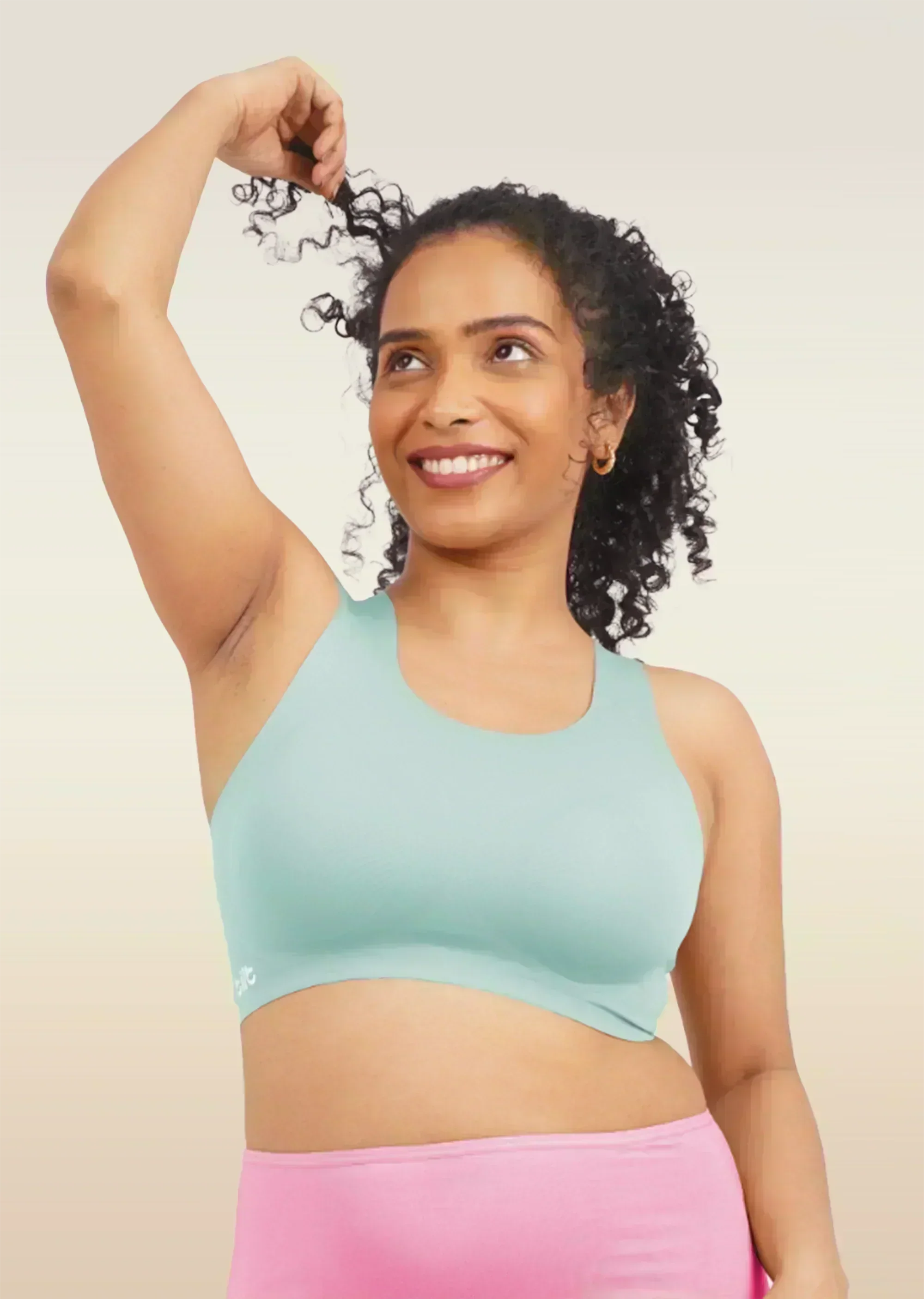 Woman wearing a blue sports bra and pink underwear on a beige background