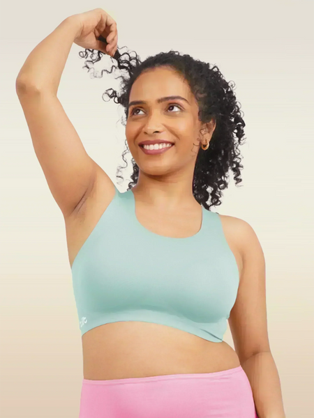 Woman wearing a blue sports bra and pink underwear on a beige background