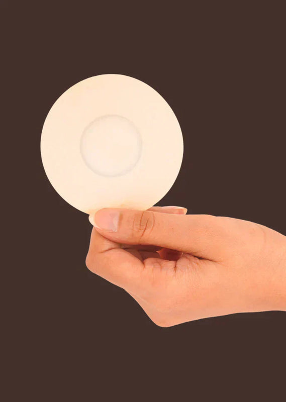 Hand holding a nipple Pastiest against a dark background