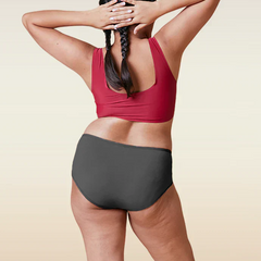 Person wearing a red sports bra and gray mid-waist underwear on a beige background