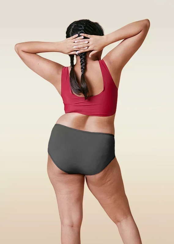 Person wearing a red sports bra and gray mid-waist underwear on a beige background