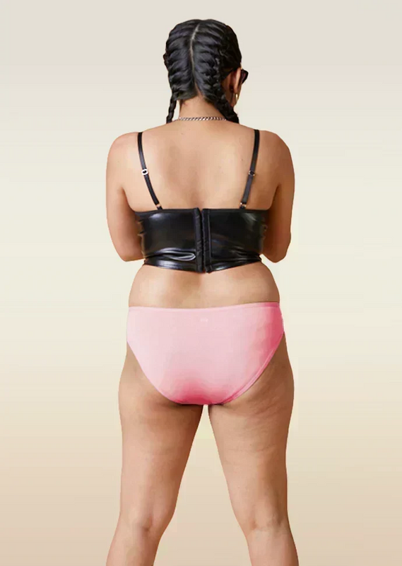 Person wearing a black leather corset and pink underwear on a beige background