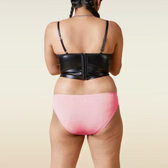 Person wearing a black leather corset and pink underwear on a beige background