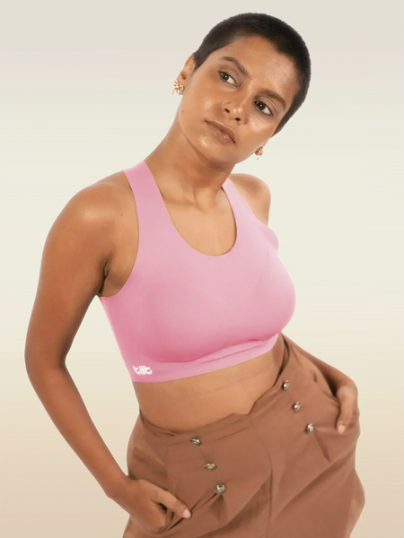 Person wearing a pink sports bra and brown pants on a plain background
