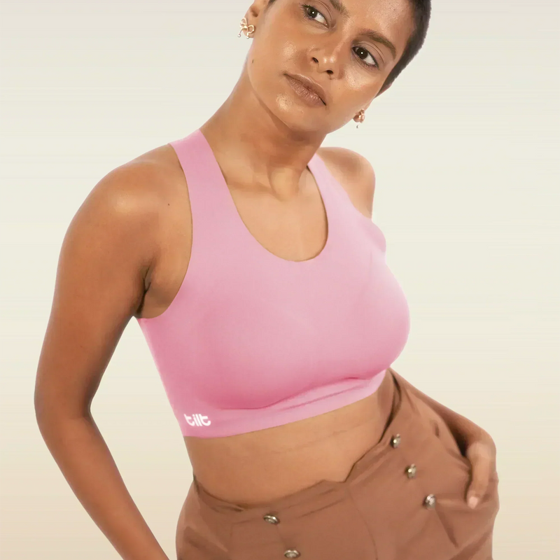 Person wearing a pink sports bra and brown pants on a plain background