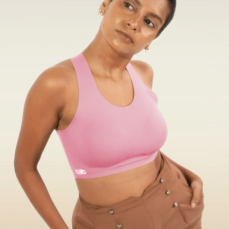 Person wearing a pink sports bra and brown pants on a plain background