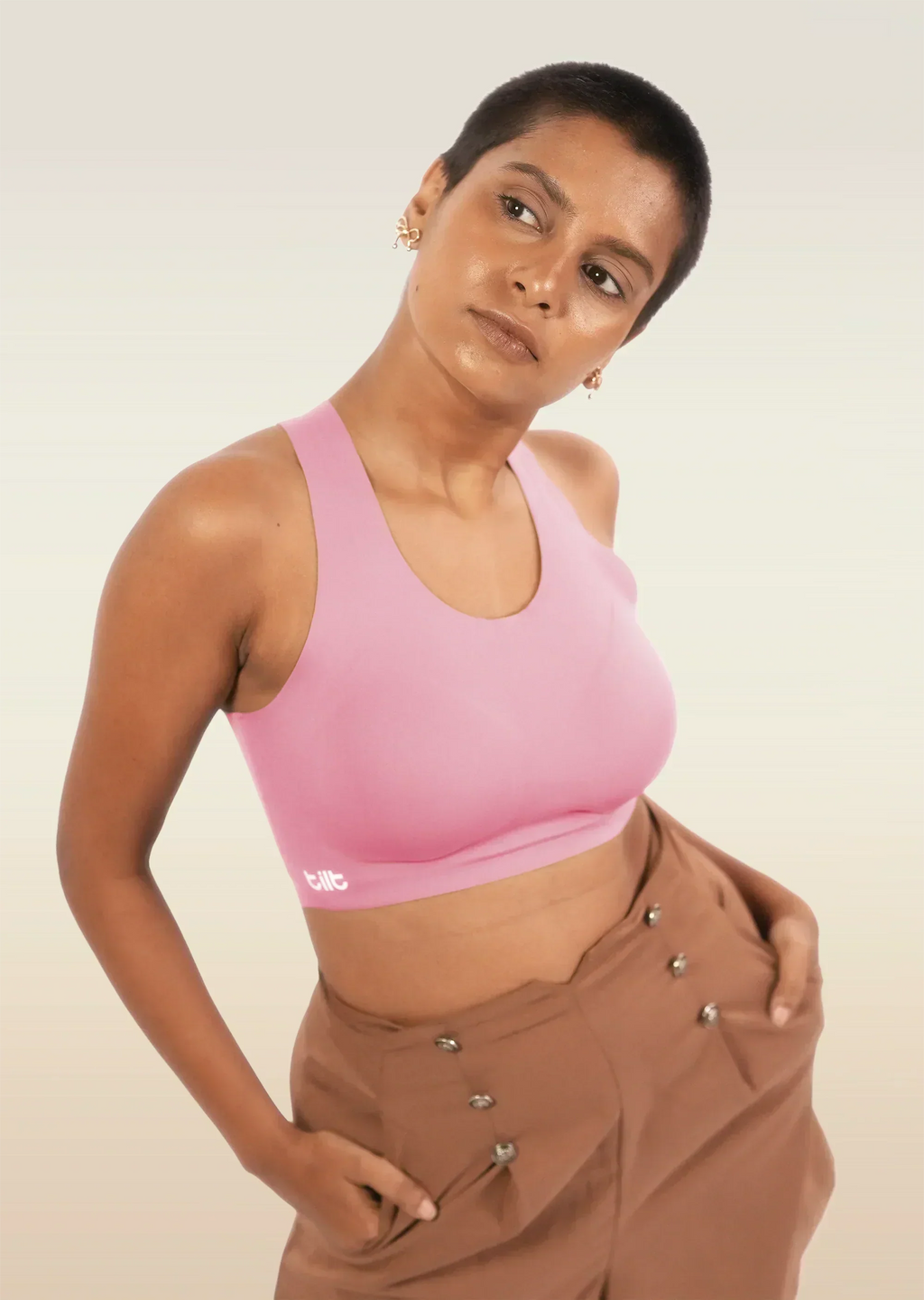 Person wearing a pink sports bra and brown pants on a plain background