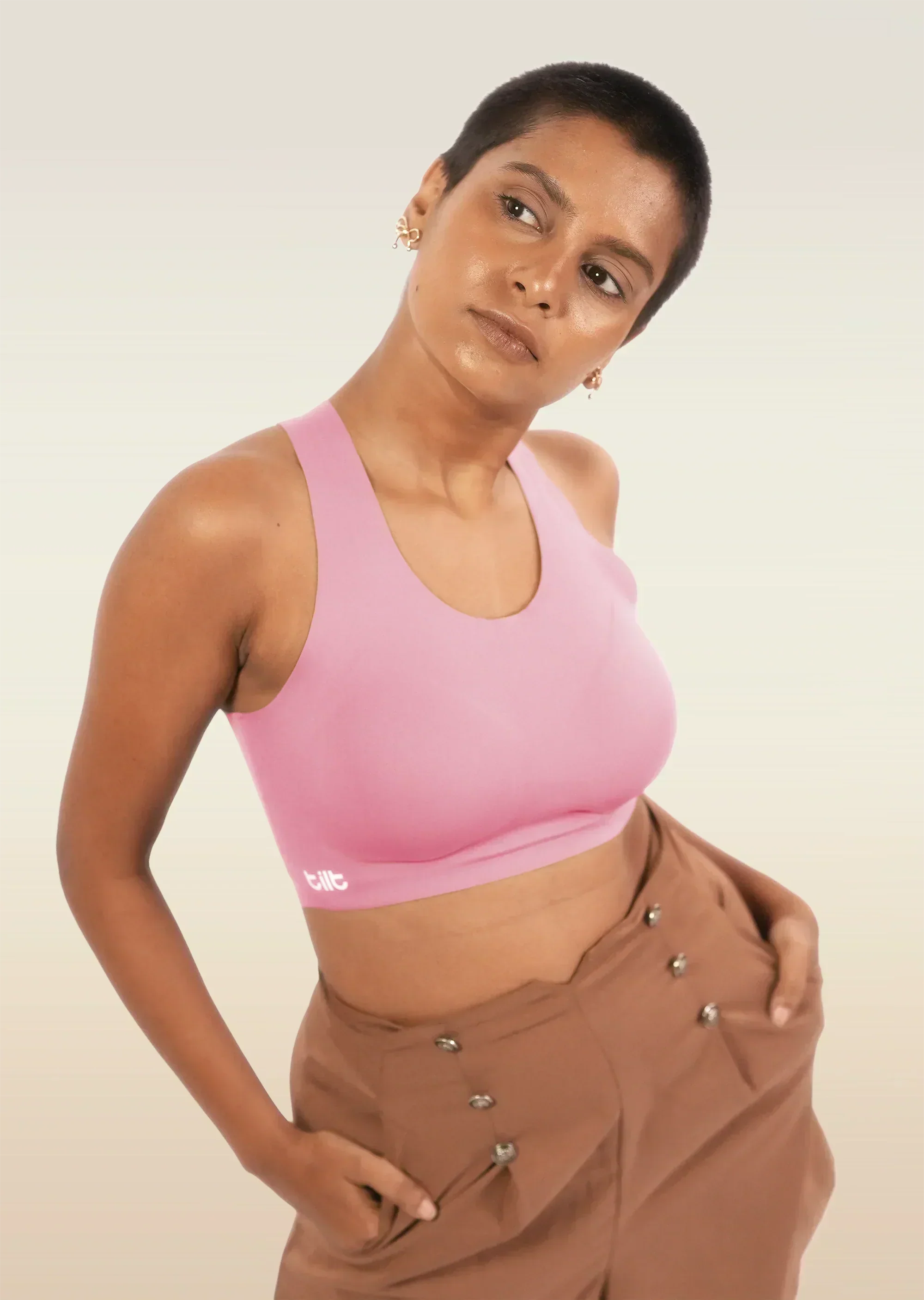 Person wearing a pink sports bra and brown pants on a plain background