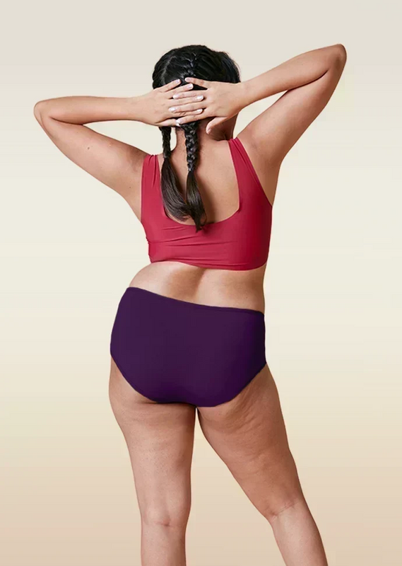Person wearing a red sports bra and  violet mid-waist underwear on a beige background