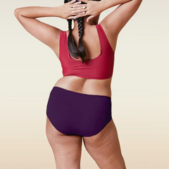 Person wearing a red sports bra and  violet mid-waist underwear on a beige background